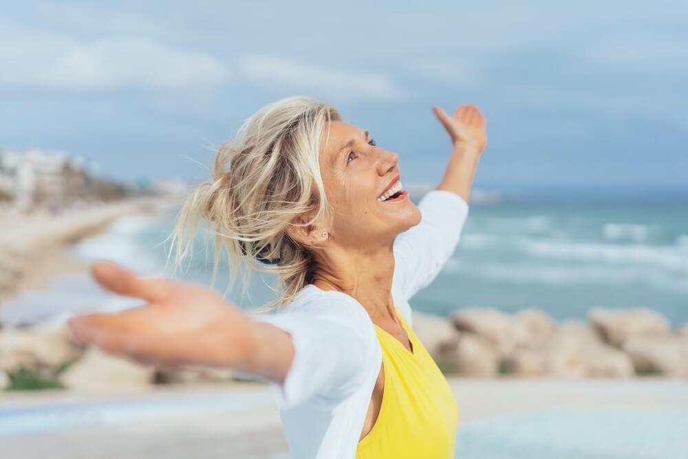 woman smiling with arms stretched out on the beach